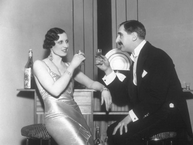 January 1932:  A couple enjoy a drink, in a scene from the play 'Last Coupon', at the Garrick Theatre, London.  (Photo by Sasha/Hulton Archive/Getty Images)