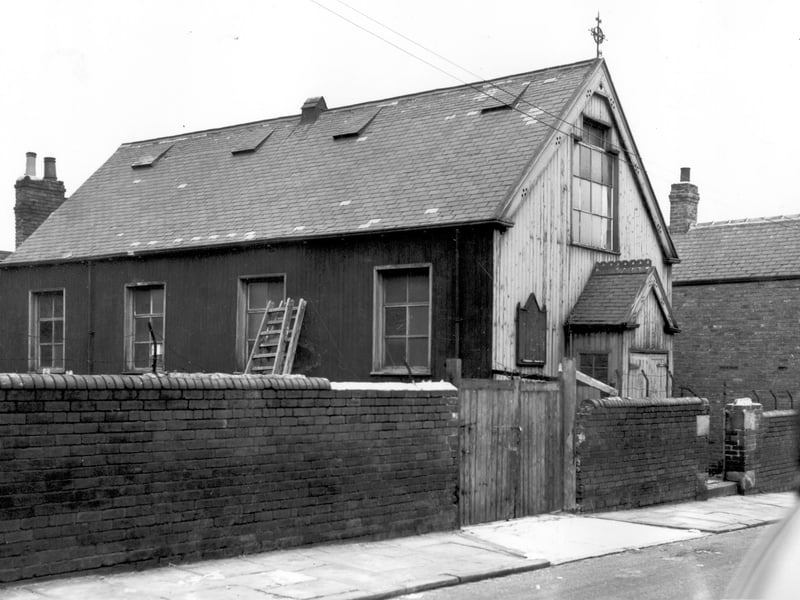 the Good Physician Church of England Mission Room on Folly Lane. Two ladders are propped up against the side wall of the hall on the left while on the right is the gable end with entrance porch and notice board. An iron cross stands on the ridgepole of the hall and on the far right can be seen number 10 Folly Lane. Pictured in October 1963.