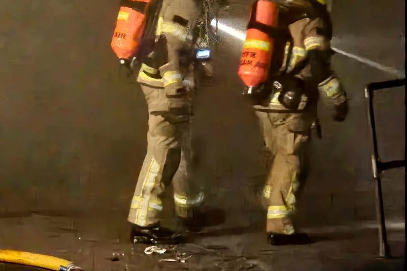 Firefighters use powerful torches to see through the thick smoke