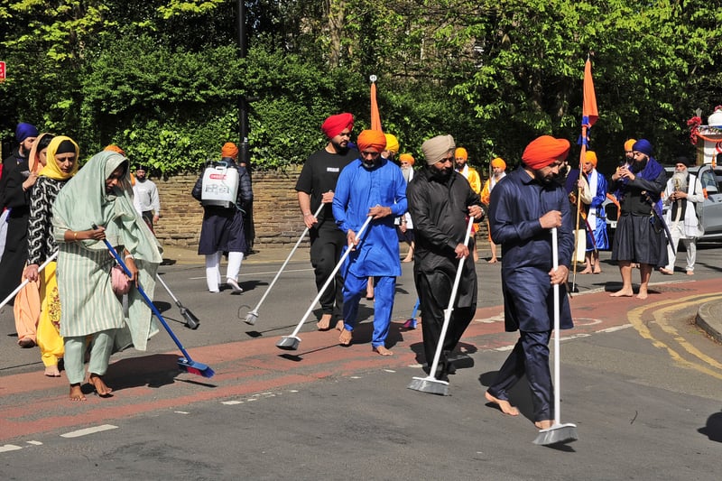 Volunteers sweep the streets in front of the parade as they take part in the procession