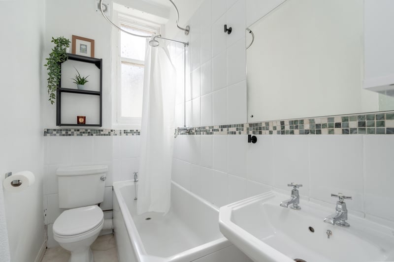 The partially tiled bathroom with three-piece suite and shower over bath.