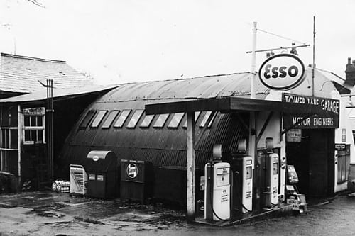 Tower Lane garage pictured in November 1963. The main part of the garage building is arched with a corrugated iron roof. Three petrol pumps are visible selling Esso Extra, Esso Mixture and Esso Golden. This garage also carried out repairs and was owned by I.M. and C. Britton.