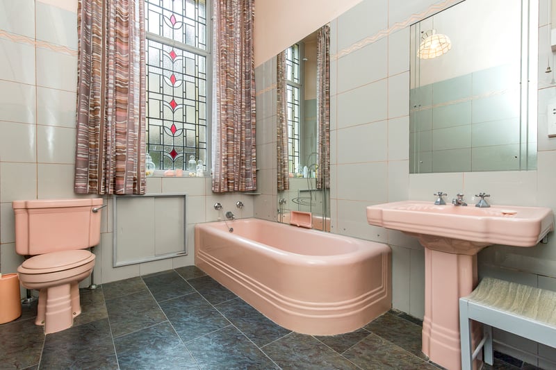 The home is served by a large bathroom with built-in storage The bathroom window is particularly impressive for its length and stained-glass detailing, adding lots of character to the space.