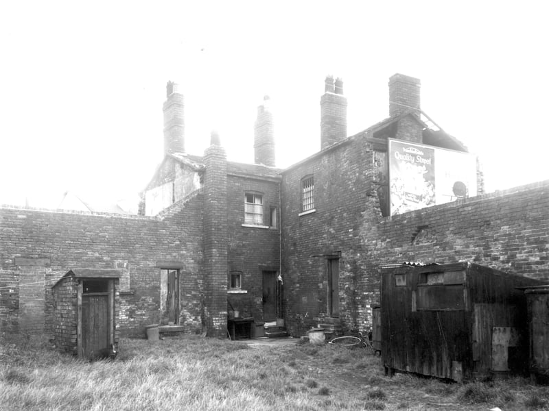 This view looks across the grassy yard of two properties, number 142 Buslingthorpe Lane to the left and number 284 Meanwood to the right. On the left is an outside toilet with a wooden outbuilding to the right. Pictured in August 1962.