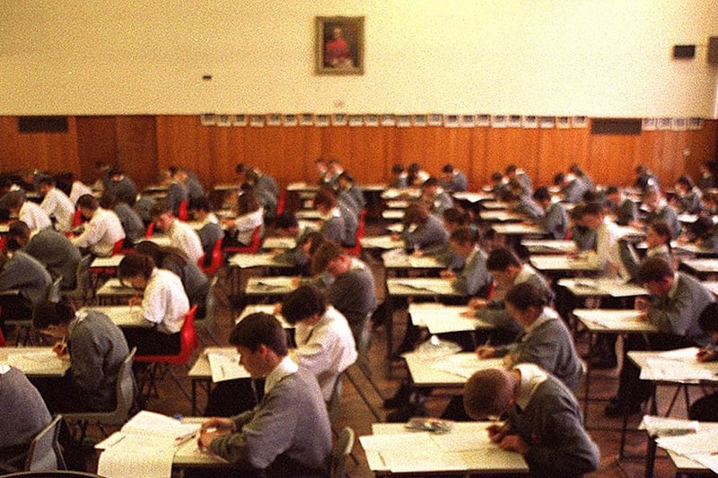 Pupils take exams in the school hall while the roof leaks in June 1998..