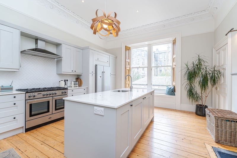 The extremely stylish fitted kitchen/dining room with central island, integrated appliances, range cooker, solid stone worktops and marble fireplace.