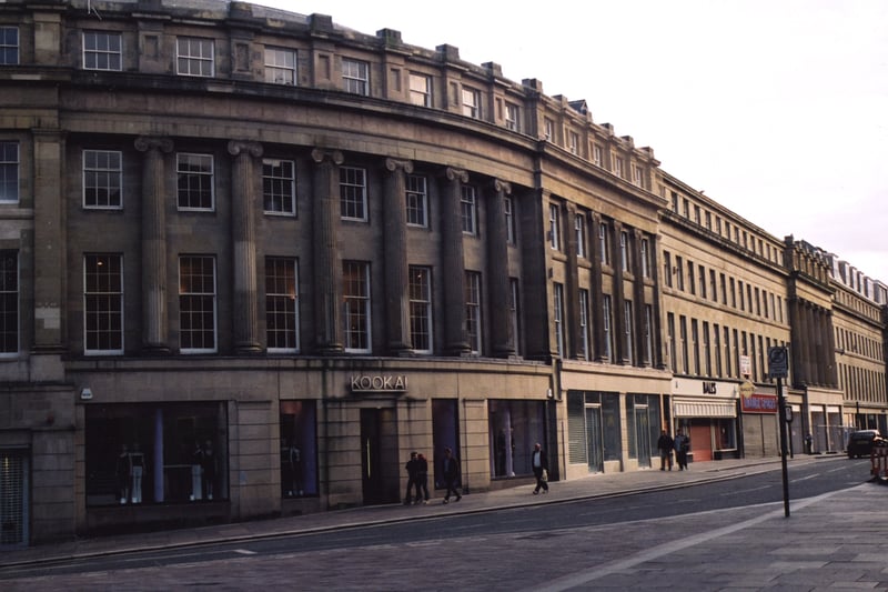 A view of left-hand side of Grainger Street Newcastle upon Tyne taken in 2002. The photograph is looking along Grainger Street from Market Street. In the foreground to the left is Market Street. 'Kookai' is on the ground floor of the building on the corner of Grainger Street and Market Street the next two shops are empty then 'Ball's' and 'McGurk Sports'. 