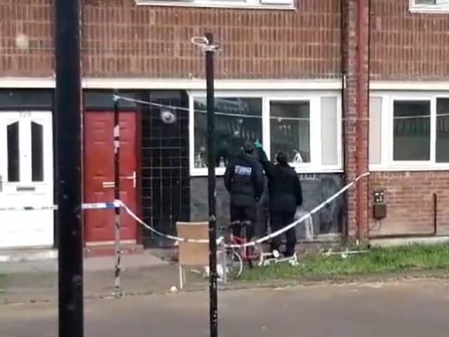 Police officers point at apparent bullet holes in windows of a flats on Lowedges Road, Sheffield. South Yorkshire Police has confirmed multiple shots were fired at the building overnight on April 24.