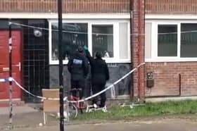 Police officers point at apparent bullet holes in windows of flats on Lowedges Road, Sheffield. South Yorkshire Police has confirmed multiple shots were fired at the building overnight on April 24.