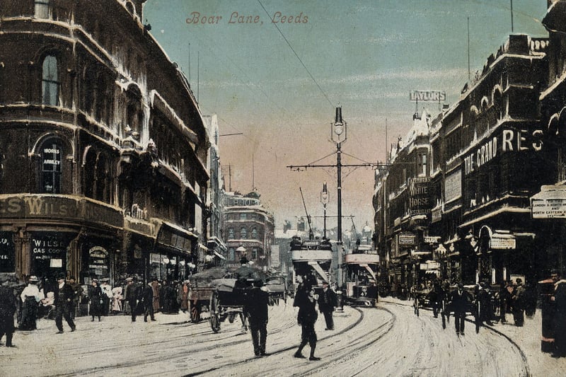A postcard view looking east along Boar Lane. On the left, by the junction with Albion Street, is Wilsons Ltd., gas cookers and stoves. On the right, after the junction with Alfred Street, is the Grand Restaurant, with Fairburn's White Horse Restaurant further along. Many people are out and about despite a covering of snow on the ground.