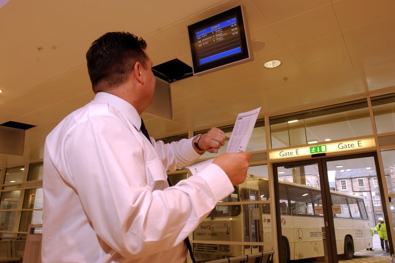 Security guard Steven McDonald reviews a bus time-table beneath the new "airport" style electronic departure screens inside the new bus station, February 2003.