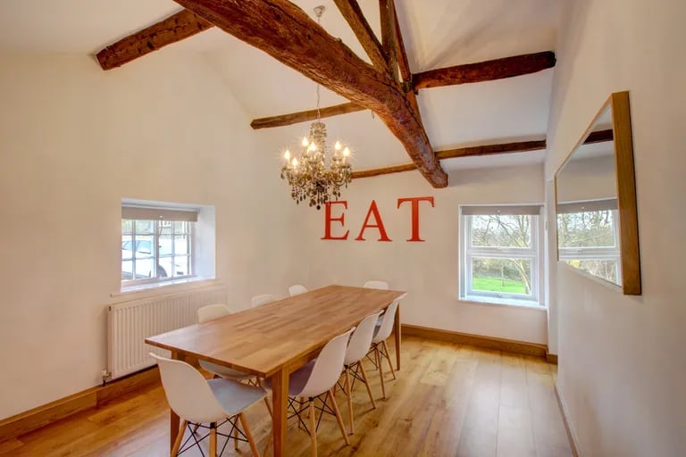 A separate dining room with stylish ceiling beams sits next to the kitchen.