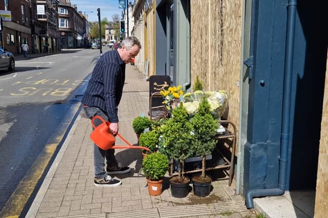 Jonathan Bagge watering the flowers as he opens up his florist on Glossop Road after its window was broken. Picture: David Kessen, National World