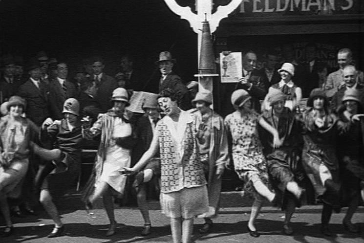 Jennie Hartley, one of the cast of the 1926 Winter Gardens Pavilion revue Brighter Days singing in front of a song booth, joined by dancers,  at the Pleasure Beach