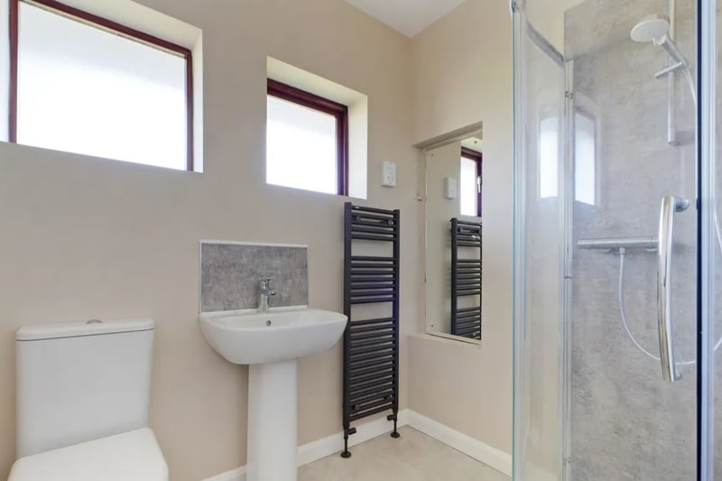 The bathroom is made up of a toilet, sink, shower and heated towel rail