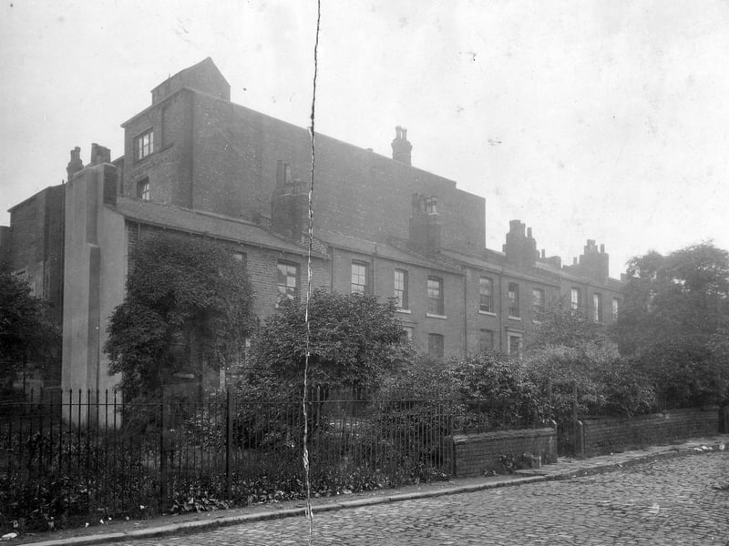 Buildings at St. James Square, proposed site of the new Municipal Offices.The buildings are bounded by railings, brick wall, and trees. The road in the foreground is cobbled. Pictured in July 1930.