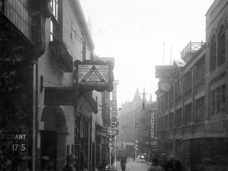 A view from Commercial Street to Boar Lane in May 1930. On the left, number 22 is the Ostlers Arms, landlady Mrs Mary Ann Best. Sign details smoke room, home brewed mild and bitter beers, refreshments. At number 23 were George Rushton's Dining Rooms. Number 24 was multi-occupied including Marshall Brothers carriers, and P. Thomson shipping agent. Number 25 was also used by various companies including James H. Thompson engraver, Arthur Myers printer and the Atlas Express Company. On the right, sign for Johnson's Engravers Ltd,