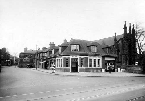 A view from Otley Road, branch of Westminster Bank at the junction. To the right of the bank is number 67, William Fawcett, newsagent then Headingley Methodist Church. On side wall of grocers shop at number 10 North Lane is sign 'Wm. Butler, the practical grocer'. To the right, Leeds Rating Authority office. Pictured in October 1931.