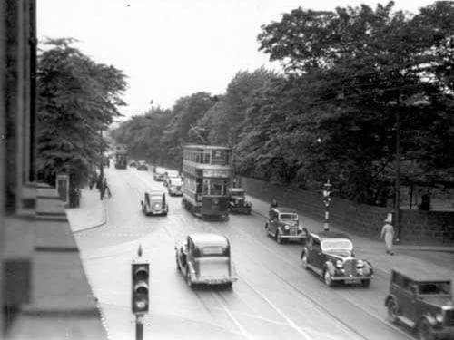 Cross roads with Traffic lights, North Lane is to the left, Wood Lane on the right. the wooded area to the right is now the Arndale Centre. Vehicles in the road include cars and trams. Pictured in June 1937.