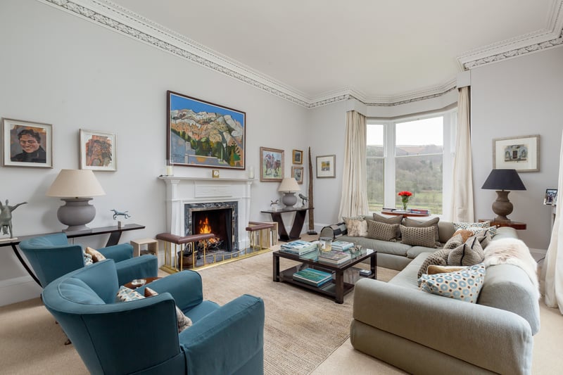 A large dual-aspect drawing room features an attractive fireplace and bay window, filling the space with light.