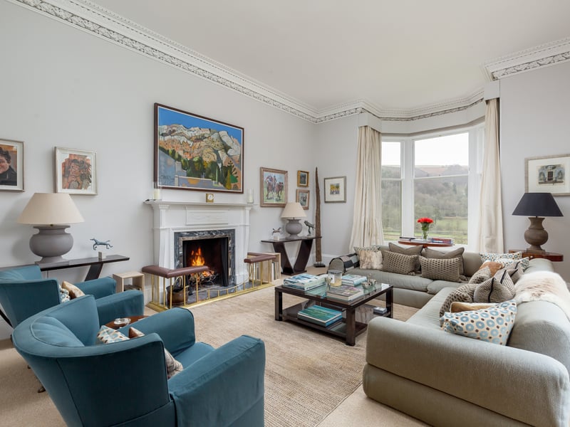 A large dual-aspect drawing room features an attractive fireplace and bay window, filling the space with light.