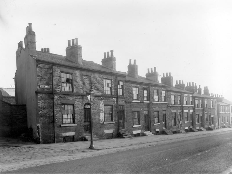 Long view of Dolly Lane looking towards Cherry Row in October 1958. The junction with Primrose Place can be seen far left. The first of the back to back brick built terraced houses on the left is number 24 and numbers descend right in an even sequence. This locality of Newtown was scheduled for demolition and is now part of the Lincoln Green estate. An LCT (Leeds City Transport) bus stop is attached to the street lamp on the corner.