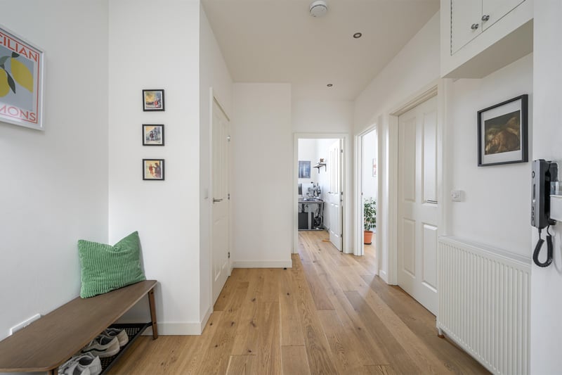 The spacious hallway has a large storage cupboard and seating area and leads through to the open plan kitchen and lounge.