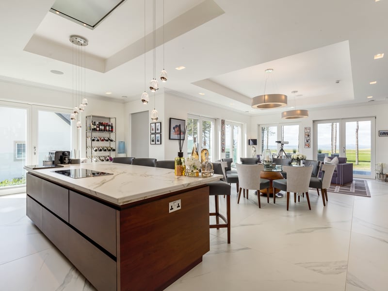 The interior space has windows and doors that frame the scenery beautifully.
Exterior: The house is situated in an enviable 0.6-acre corner plot with trees aligned down one side. The low-maintenance landscaped garden includes lawns and thriving plants. Its detached garage has a gym.
