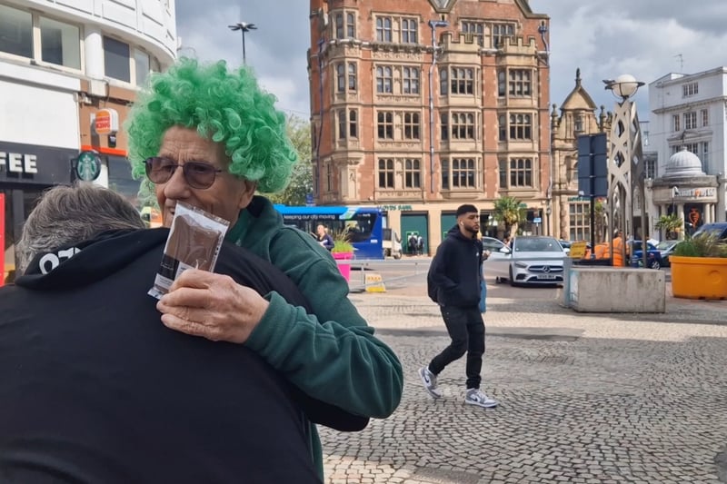 A fan and friend of John's hugs him in the street.