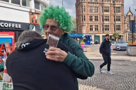 A fan and friend of John's hugs him in the street.