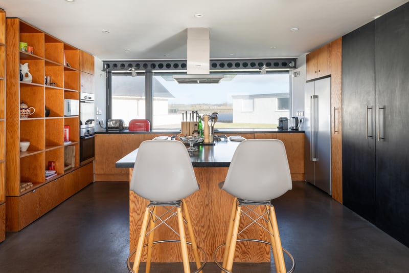 Light streams in from the glazed floor to ceiling windows in the open-plan kitchen dining room where dolphins can often be spotted. The floor is finished in contemporary polished cement.