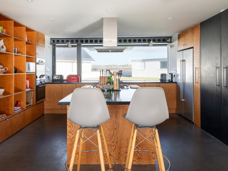 Light streams in from the glazed floor to ceiling windows in the open-plan kitchen dining room where dolphins can often be spotted. The floor is finished in contemporary polished cement.