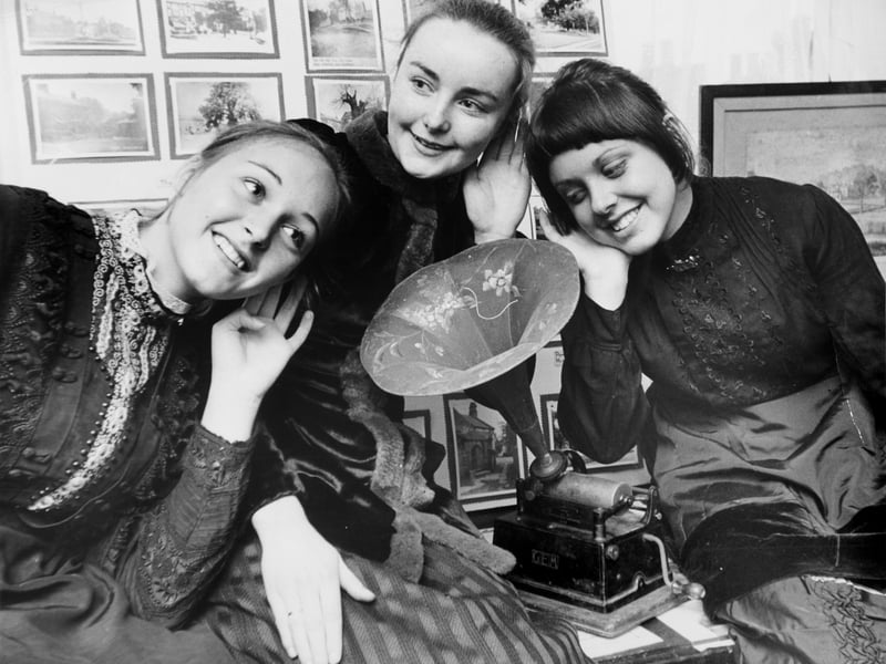 A phonograph was on display at an exhibition being held at the Brown Cow Hotel in September 1974 to give an idea of long ago life in the village. Listening to its music are Diane Ward, on left, Christine Barnard, and Andrea Lamprey all in period costume.