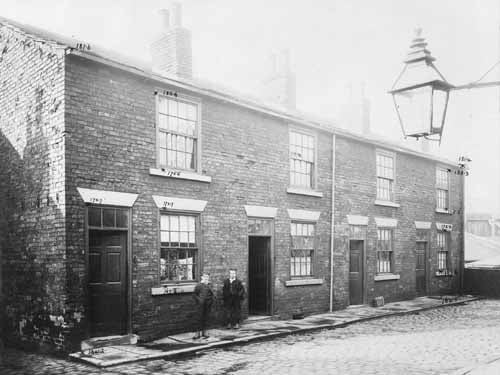 This is an unknown side street off Pontefract Lane with a row of brick built terraced houses. The street is cobbled in dressed stone and there is a gas streetlamp at top right. There are two small boys standing on the pavement. The dimensions visible are by the City Engineers Department. Pictured in October 1903.