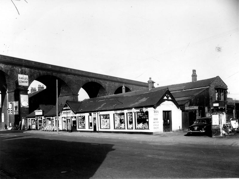 Kirkstall Road Railway Viaduct, built between 1840-1852 to carry the Leeds to Harrogate line. The long single storey building is the business of Harold Barrett Ltd, motorcycle dealer. A B.S.A stockist also selling Vespa, Lambretta scooters. On the right edge part of the yard belonging to Cox Brothers scrap metal dealers can be seen, the car is parked on Viaduct Place. Pictured in October 1959.