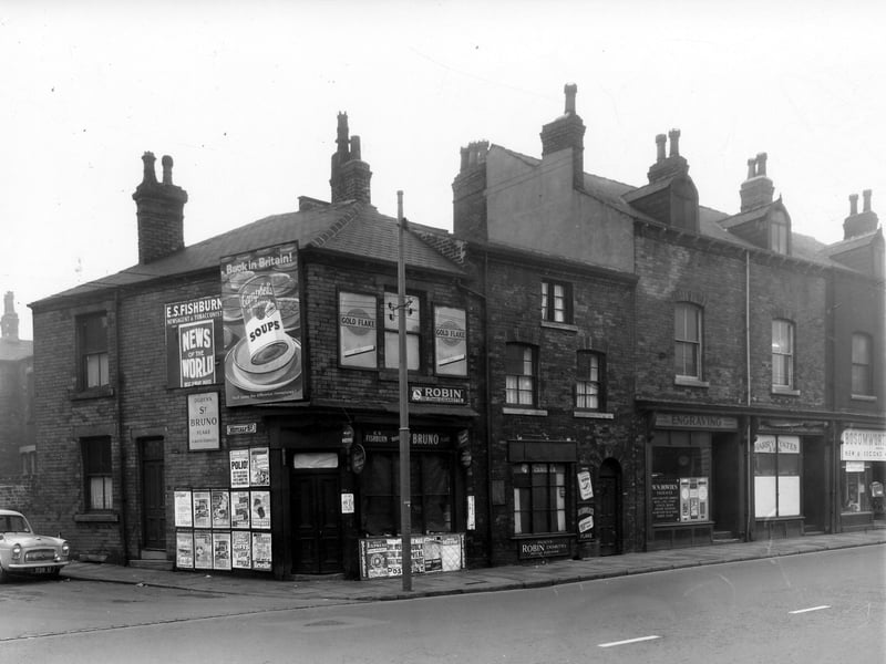 Metcalf Street is on the left, the newsagents shop at the corner is number 206 Kirkstall Road, business of E.S. Fishburn. On the wall are posters for various publications. A large advertisement for Campbells soup has the slogan 'Back to Britain', referring to war time and post war restrictions. Moving right, is 204 then 202 which is the shop of W.N. Howden, engraver. Next Harry Yates and Son leather manufacturers occupy 200. On the right, part of 198, Bosomworths furniture store can be seen. Pictured in October 1959.