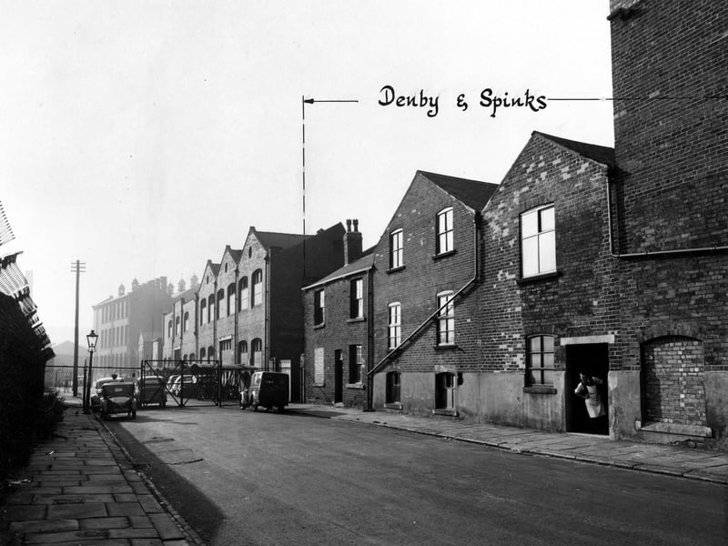 Factories of J. Best and Denby and Spinks Ltd. on Front Row in September 1946. A large metal gate and fence seal off the rest of the street. A man looks out of a doorway. Parked cars, streetlamp and a telegraph pole can be seen.