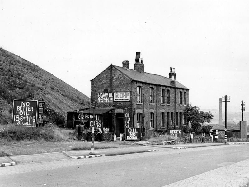 A petrol station on 164 to 168 Gelderd Road. There are several signs promoting the oil's quality. The prices are imperial. A man attends a pump. Pictured in August 1943.