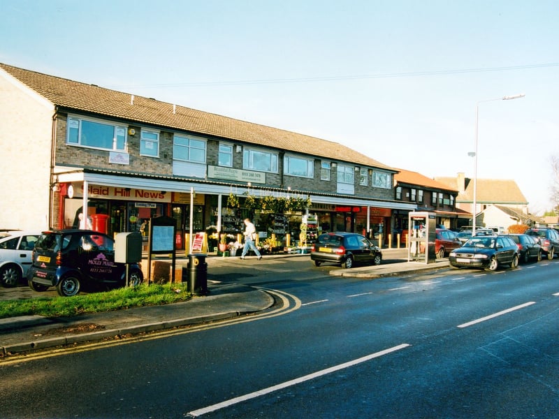 Slaid Hill Court shopping parade on Wike Ridge Lane. On the left is Slaid Hill News, there is also a pharmacy and a branch of Ainsleys bakers.