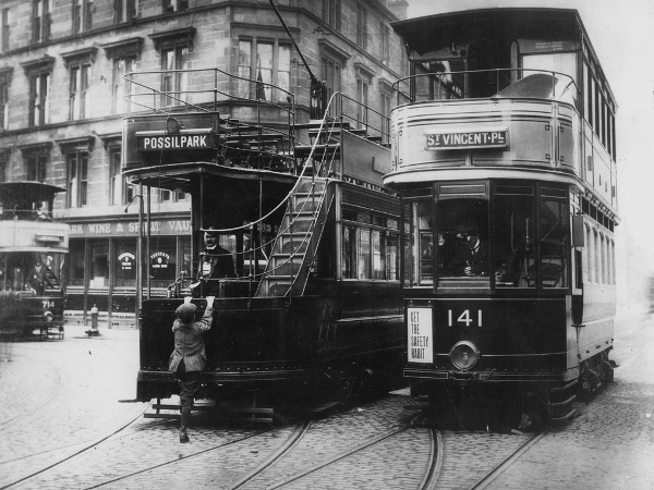 Two electric trams at the Balmore Road / Saracen Street intersection - a young boy hangs off the back of an open top tram.