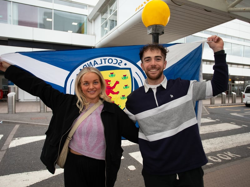 Two Scotland fans hold the saltire aloft as they prepare to enter the departure lounge for their flight to Germany.