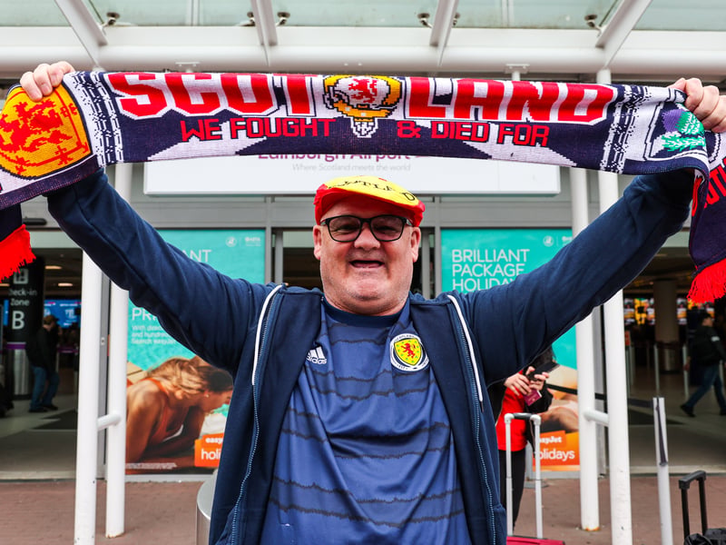 A Scotland fan raises a flag above his head.