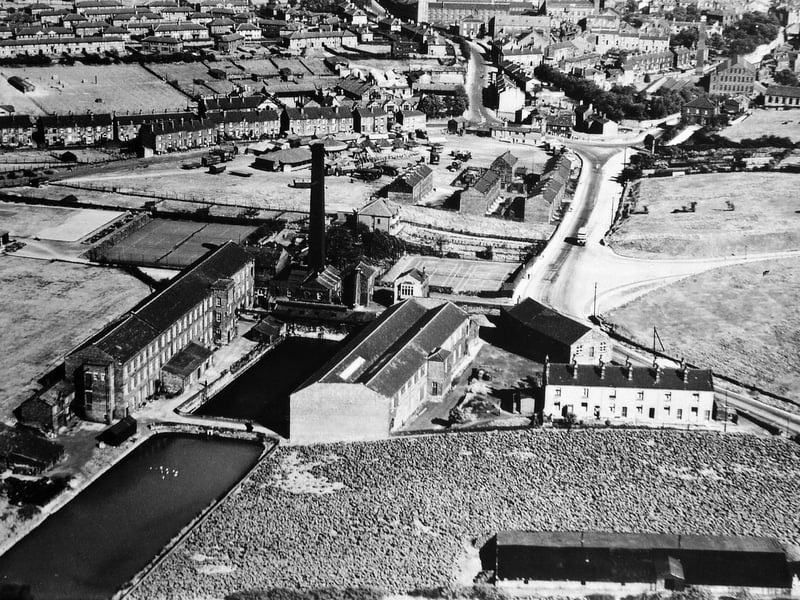 An aerial photo showing the whole of J. & D. Brooks' Dean Hall Mill in September 1933. In the foreground are rhubarb fields and sheds off Bruntcliffe Lane with a block of terrace houses called West View. On the right the newly completed through road of Corporation Street comes into Bruntcliffe Lane.