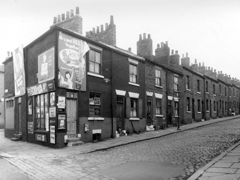 A long view of Lincoln Field Row showing grocers, G Smith on the corner. The walls of the shops are busily decorated with hoardings advertising some brands which are still available today, for instance Heinz Baked Beans, Echo Margarine and Scotts Porrage Oats. The grocers was numbered 26 Cherry Row. A dog sits on the doorstep of number 3 Lincoln Field Row. Pictured in October 1958.