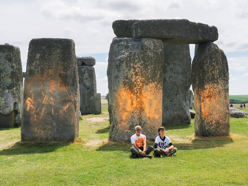 Just Stop Oil protesters sit in front of one of the Stonehenge monuments after the graffiti attack