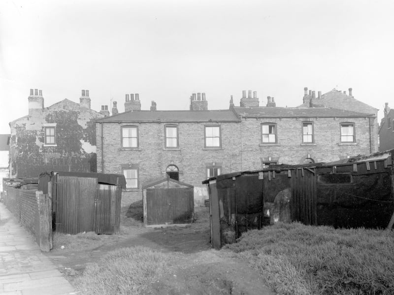 Looking across from Dolly Lane towards Primrose Place in October 1958. Two houses seen centre are number 34 Dolly Lane on the left and number 9 Primrose Place. On the right Chippendale's Yard is situated behind these houses. In the foreground are garages and shed. The flagged pavement on Dolly Lane can be seen far left.