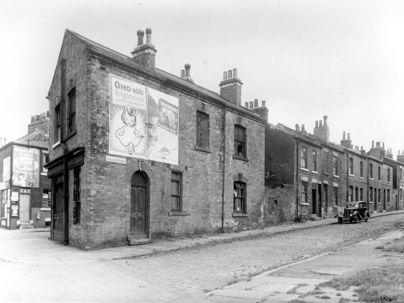 Derelict property in Lincoln Street. Fronting on to Cherry Row on the left is number 24 Cherry Row. This has been shop premises but is now unoccupied and dilapidated. It has obviously been a grocers most recently, indicated by the large advertising hoardings for 'Omo' washing powder and Rowntrees jelly but was once a pawnbrokers. Pictured in October 1958.