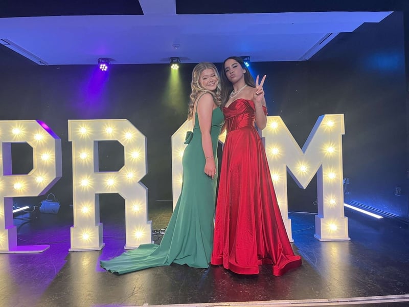 Two friends pose by the prom decoration