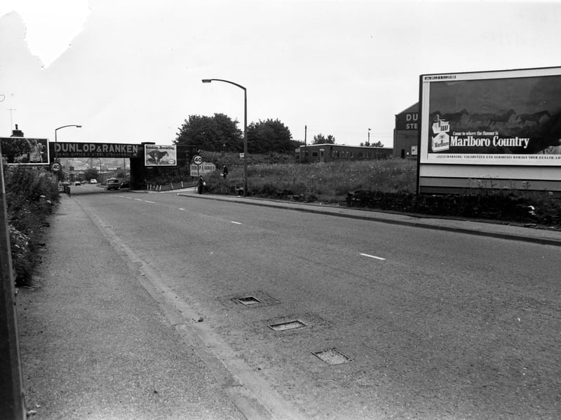 Whitehall Road showing the railway bridge on the left. An advertisement for Dunlop & Ranken Steel Service Centre is on the bridge; their works are on the right, partially hidden by an advertising hoarding for Marlboro Cigarettes. Other advertisements are either side of the bridge, including one for Esso. The junction with Branch Road can be seen by the bridge. Pictured in July 1980.