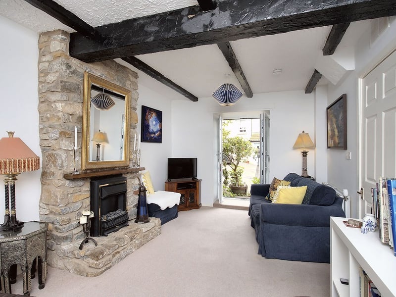 The living room spans the depth of the property, providing a delightful space for relaxing and socialising. It is bathed in lots of natural light from dual-aspect glazing, and includes French doors opening out into the home's front garden. It also benefits from neutral decoration and soft carpeting, and a focal-point fireplace embedded in a stone feature wall. Built-in storage completes the space.